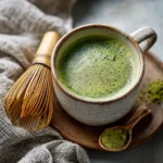 Matcha Latte Zubereitung mit Bambusbesen in Keramikschale