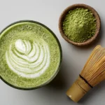 Obenansicht eines Matcha Latte mit grünem Schaum und Bambusbesen